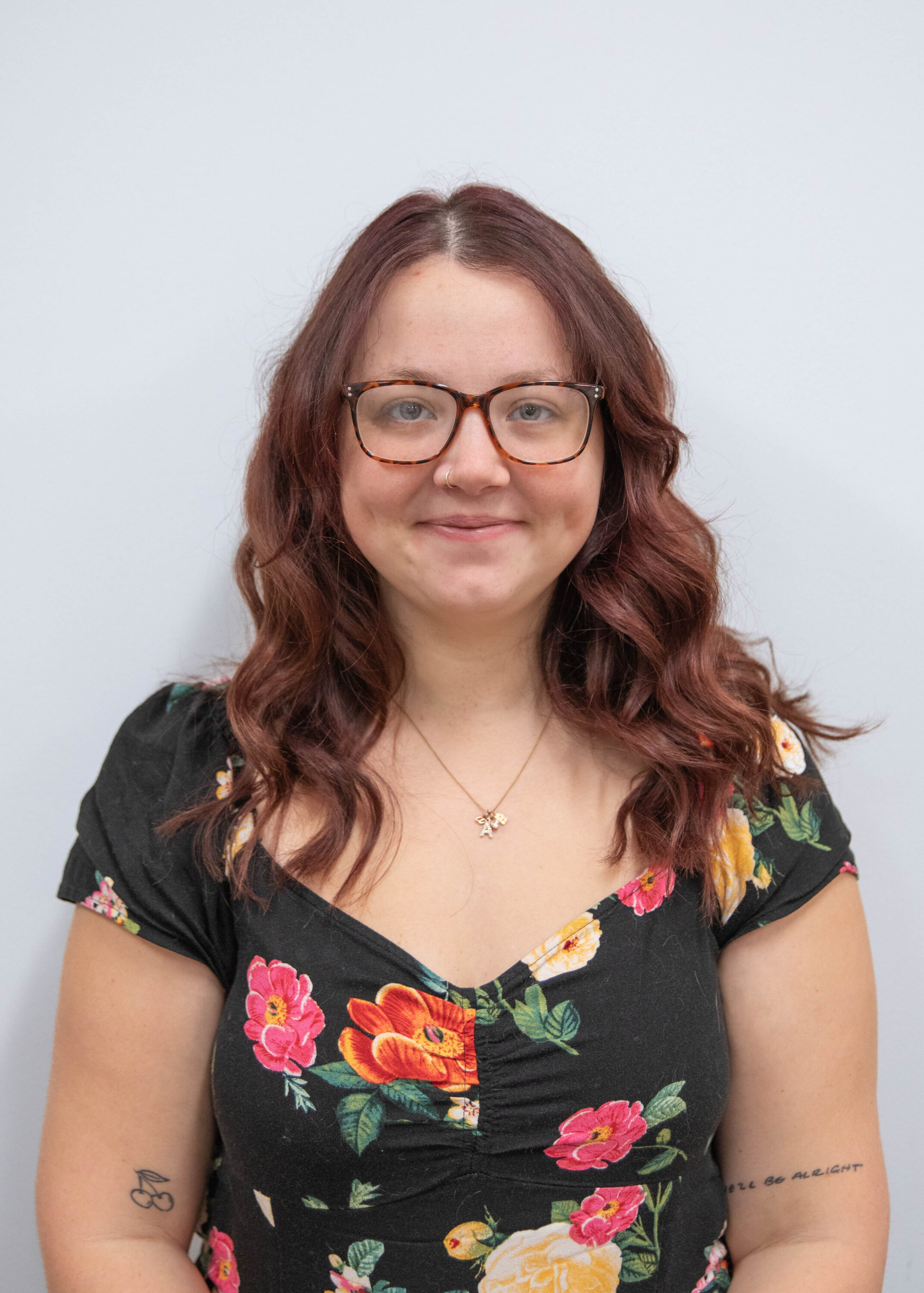 Woman with glasses and floral dress smiling