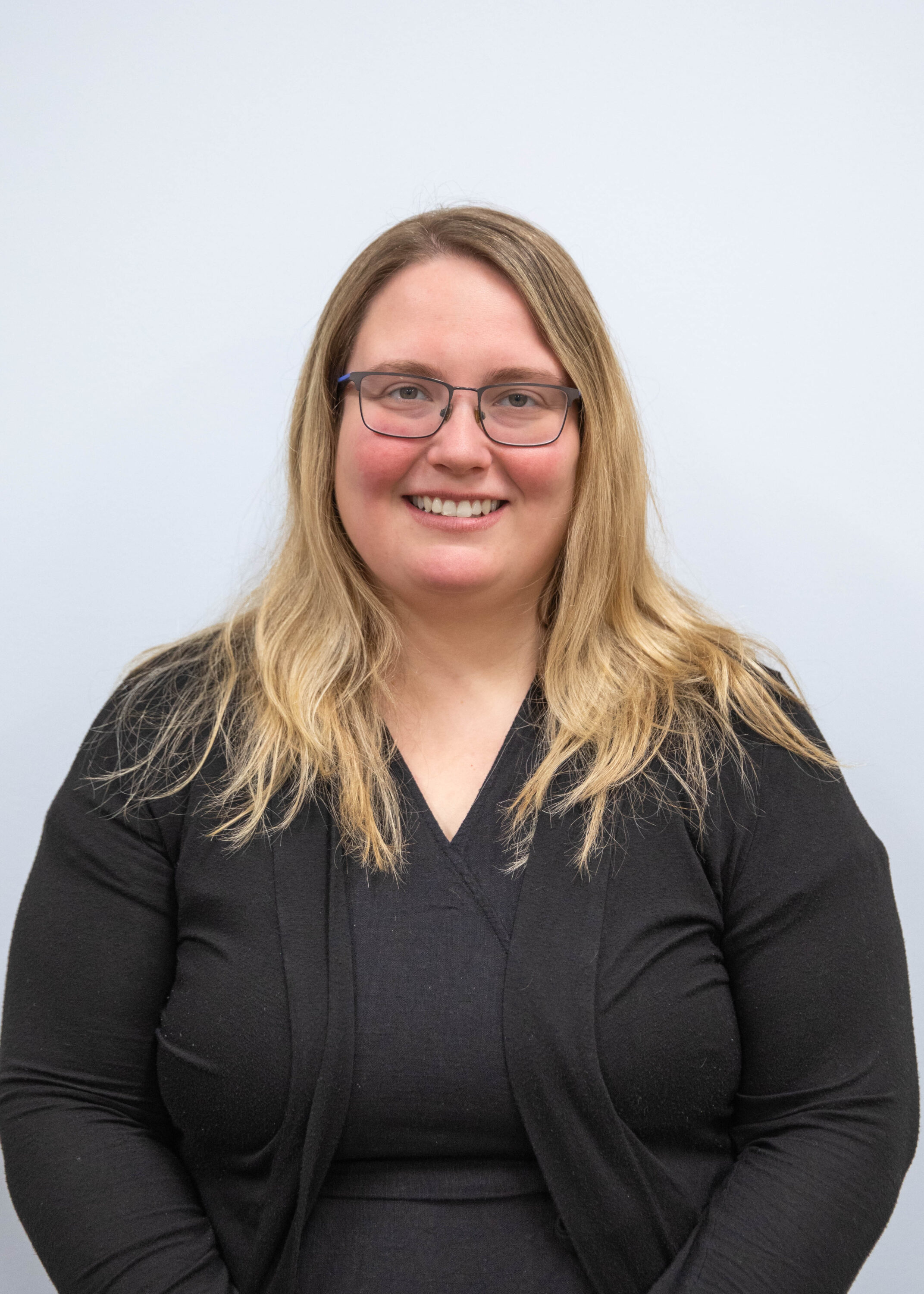 Smiling woman with glasses against neutral background