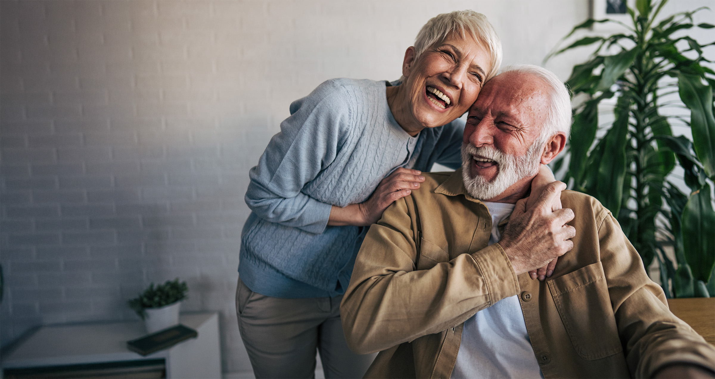 Happy senior couple laughing and embracing indoors