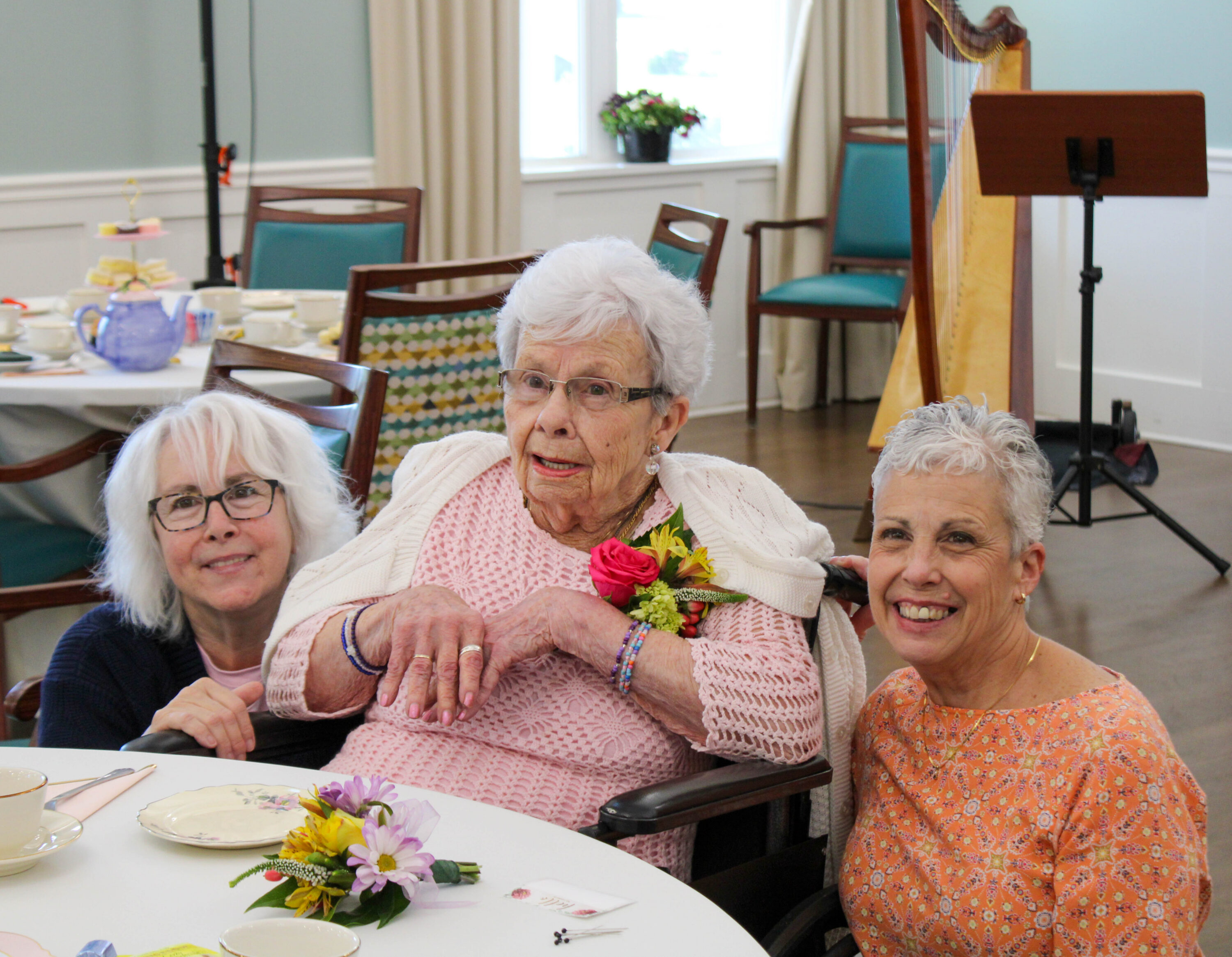 Three women smiling at tea celebration table