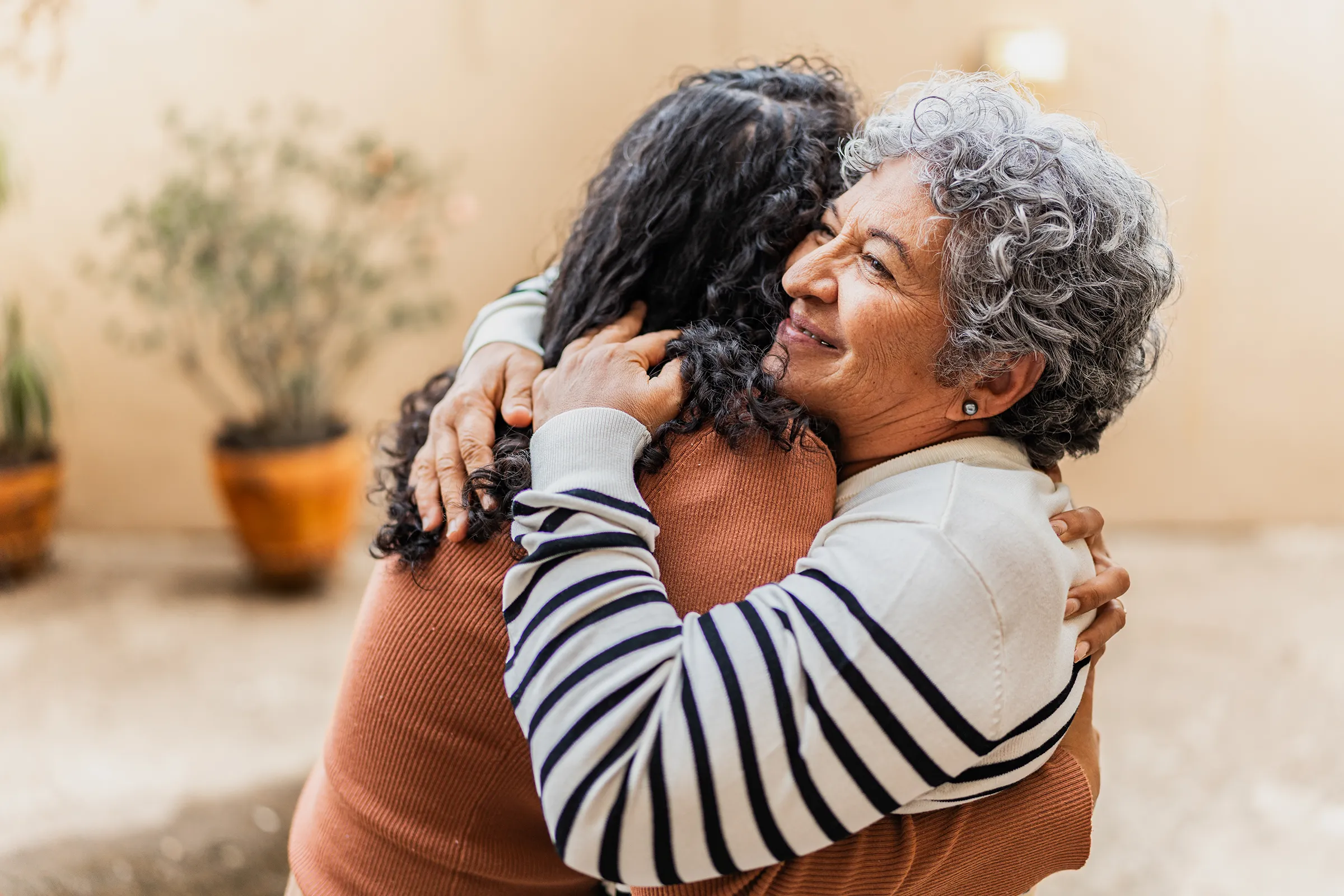 Older woman hugging younger woman outdoors