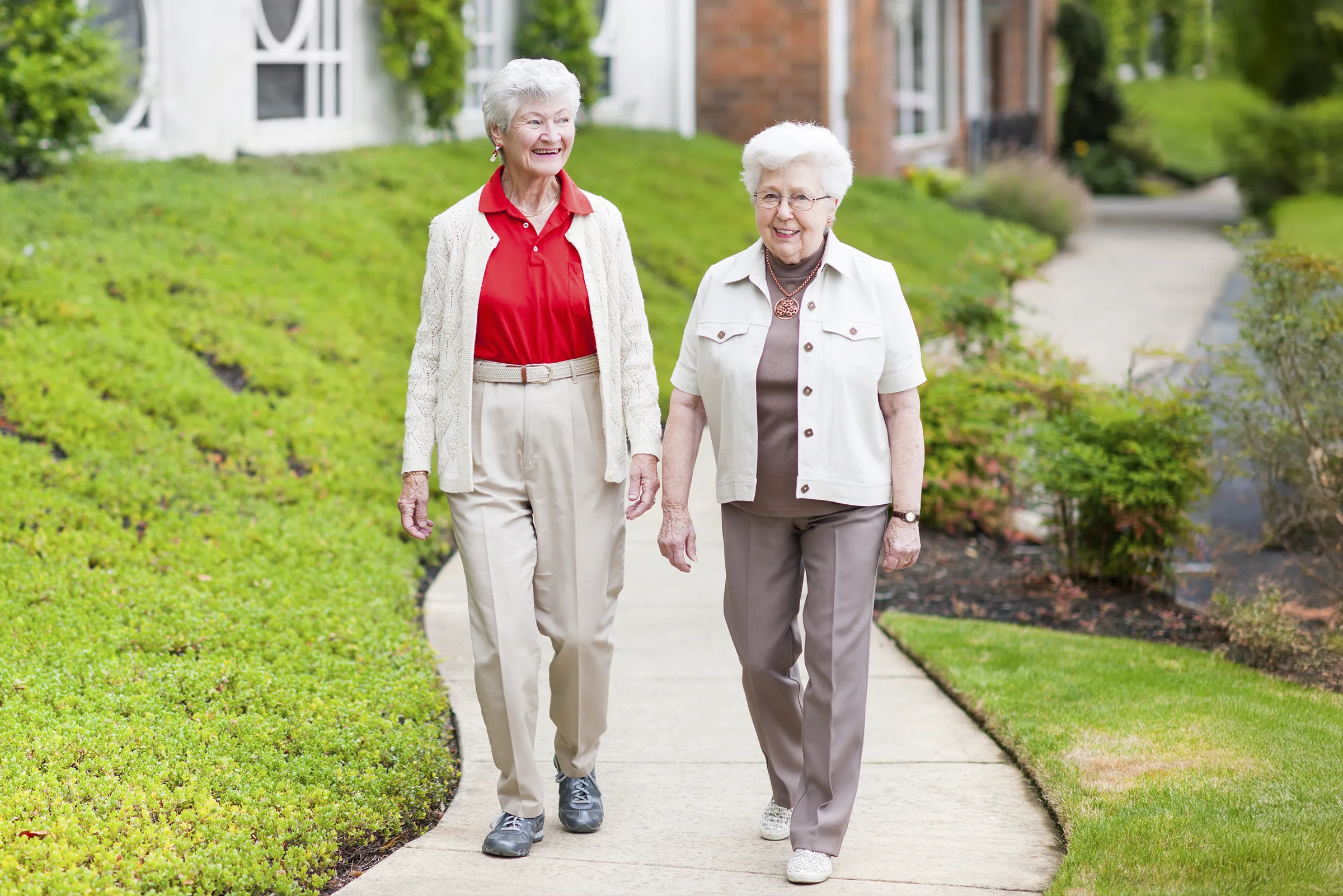 Two elderly women walking on a sidewalk