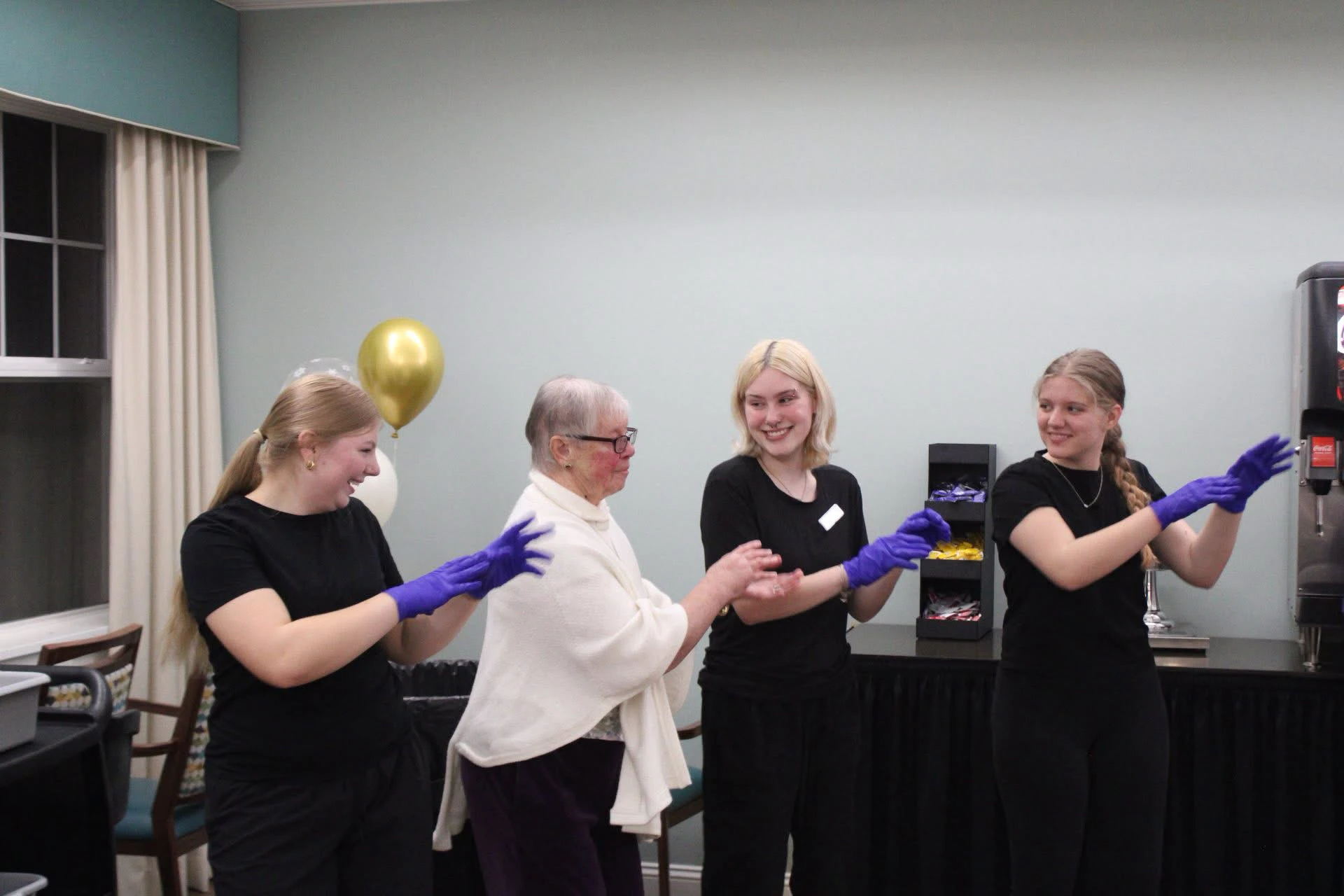 Young women helping elderly woman with gloves